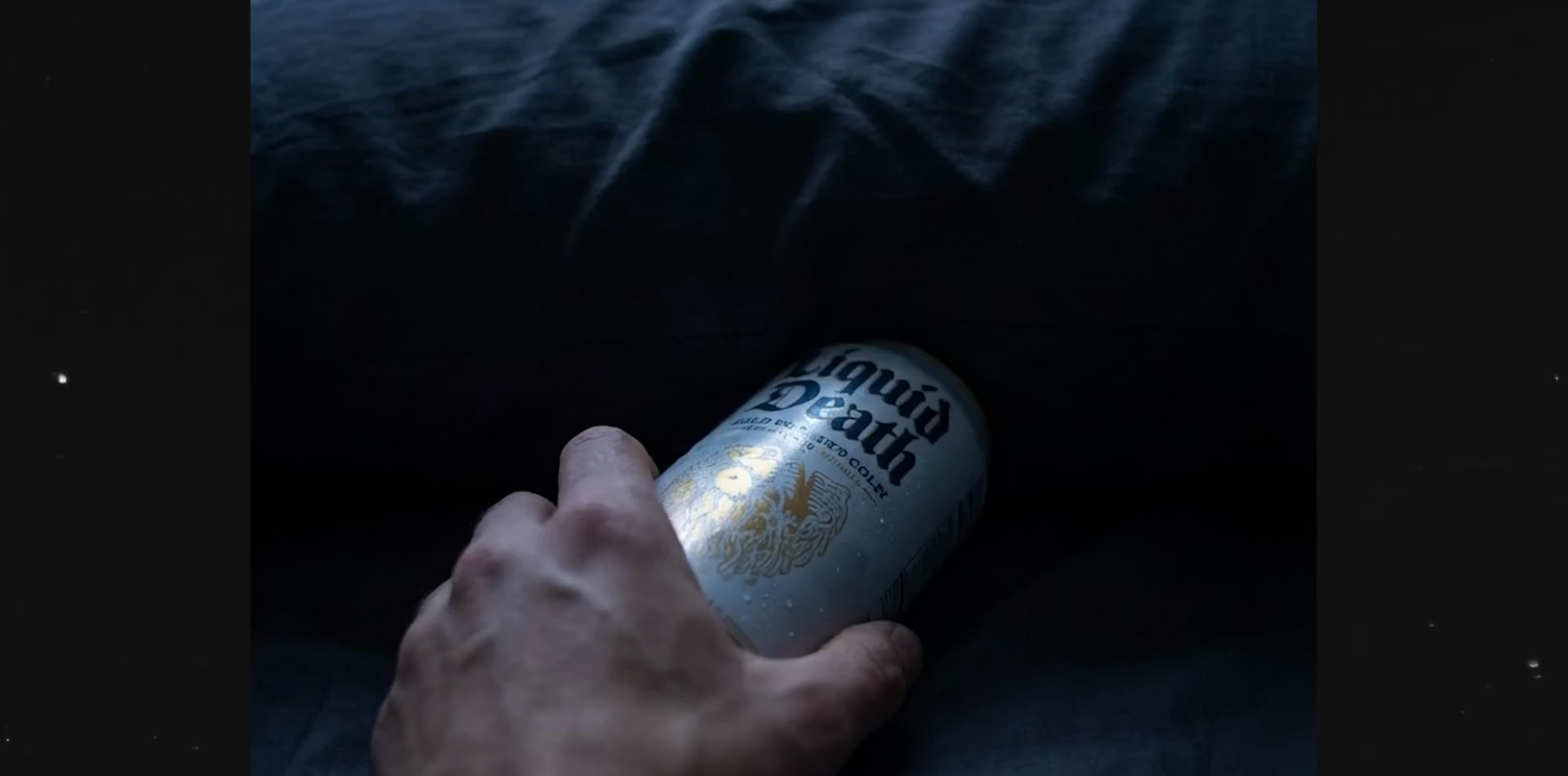 手拿罐裝產品的近鏡關鍵幀，顯示手部、罐身比例、方向與冷色床鋪背景